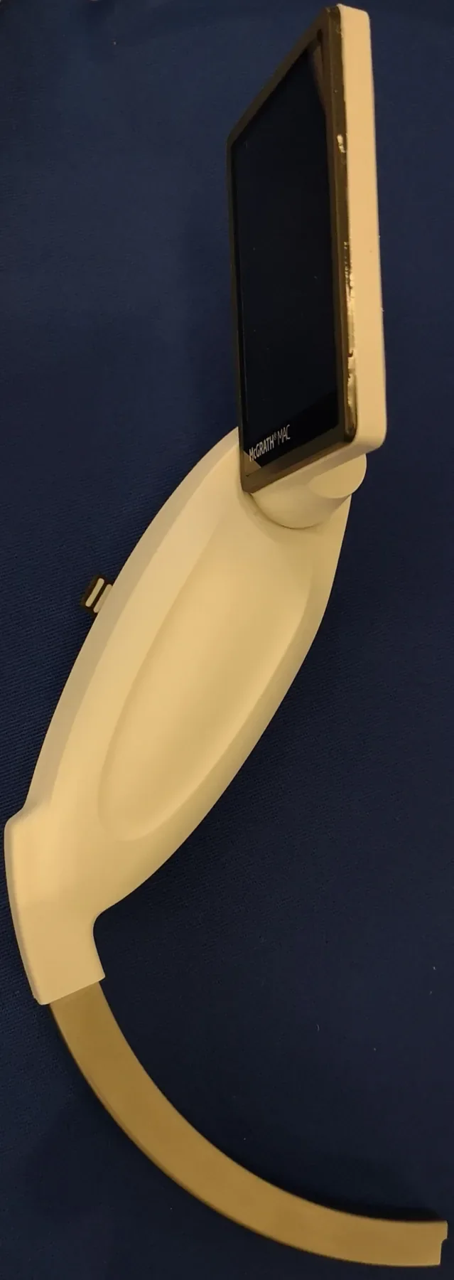 McGRATH MAC video laryngoscope with its screen, handle and curved blade against a blue background.