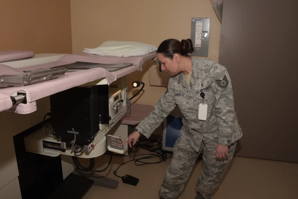 A technologist checking the imaging and needle-positioning assembly below a prone stereotactic breast-biopsy table.