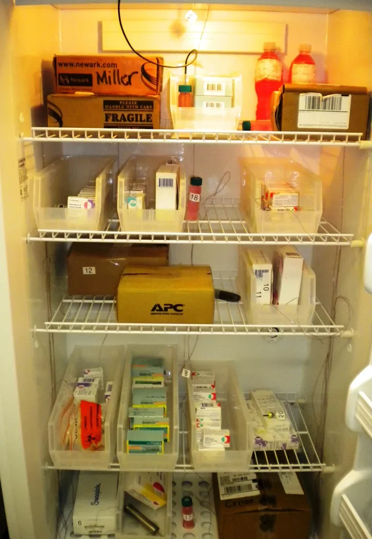 A refrigerator containing vaccine-study materials and temperature measurement equipment.