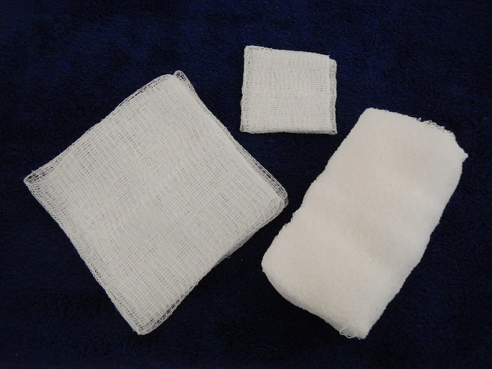 Three different medical gauze pads on a dark blue surface