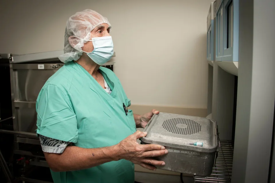Technician loading an instrument set into an open low-temperature hydrogen-peroxide plasma sterilizer