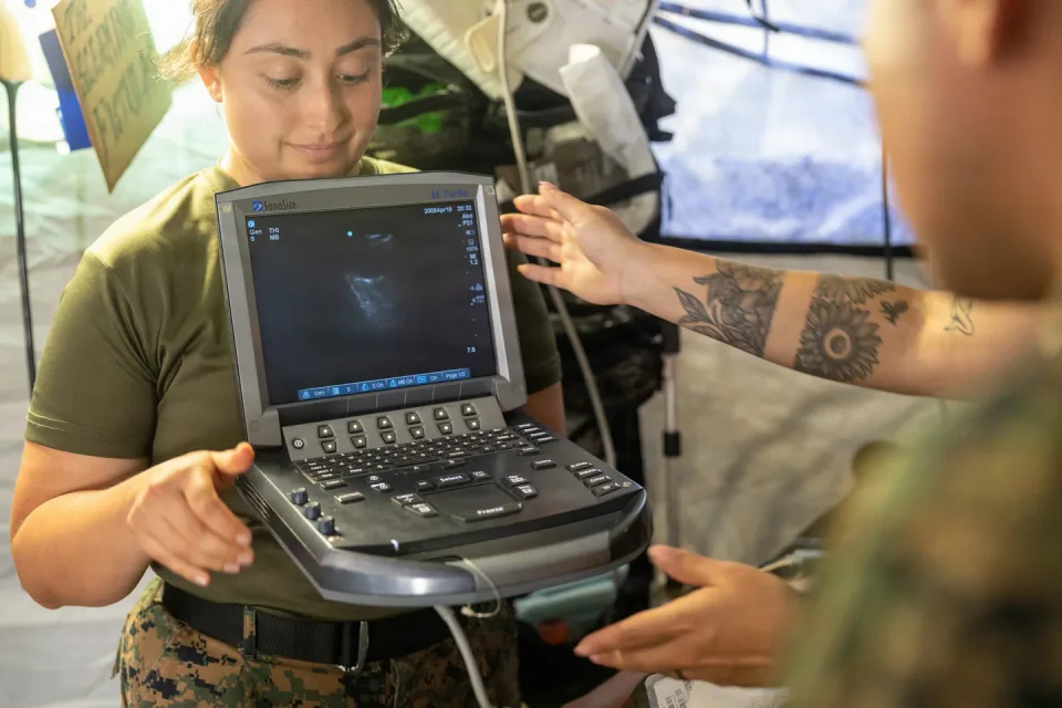 A SonoSite M-Turbo portable ultrasound with its screen and controls visible during a medical training exercise.