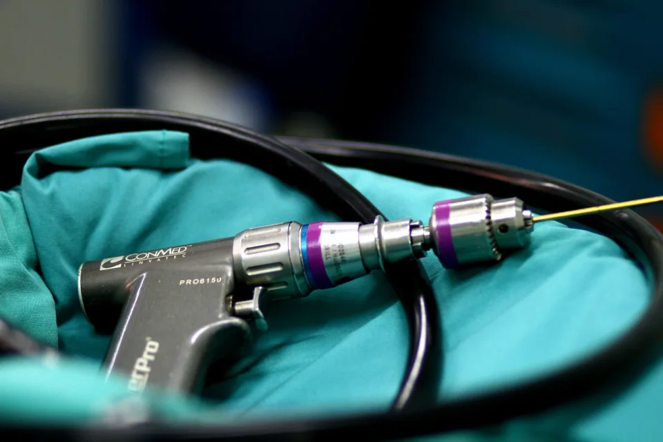 A pneumatic surgical drill resting on a surgical drape.