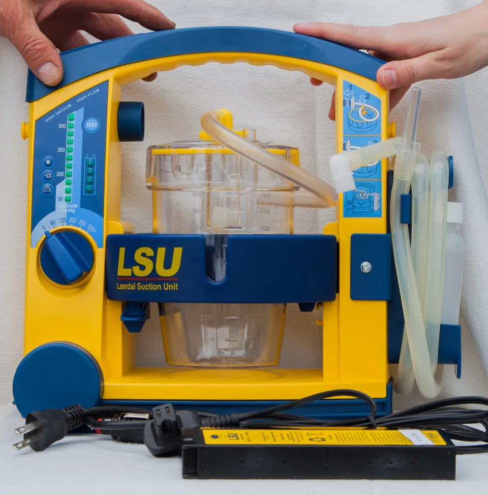 Blue-and-yellow Laerdal Suction Unit with collection canister, tubing, battery and power lead.