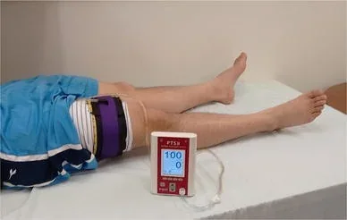 A pneumatic surgical-tourniquet cuff fitted around a thigh, beside its pressure-control console.