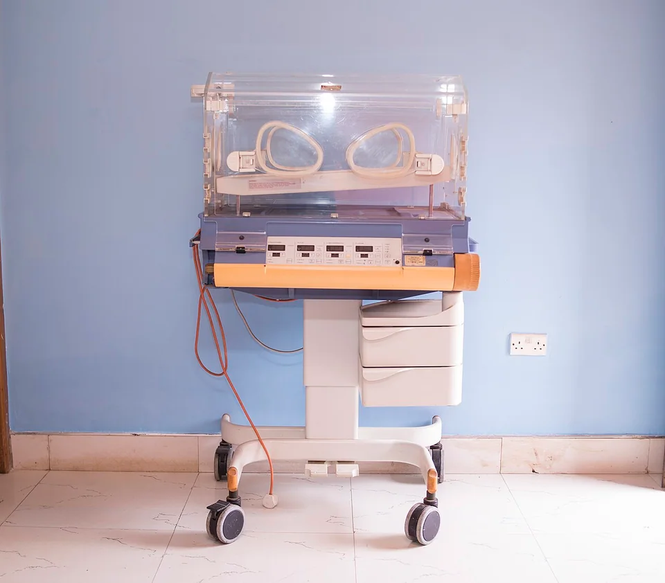 Empty infant incubator on a wheeled stand