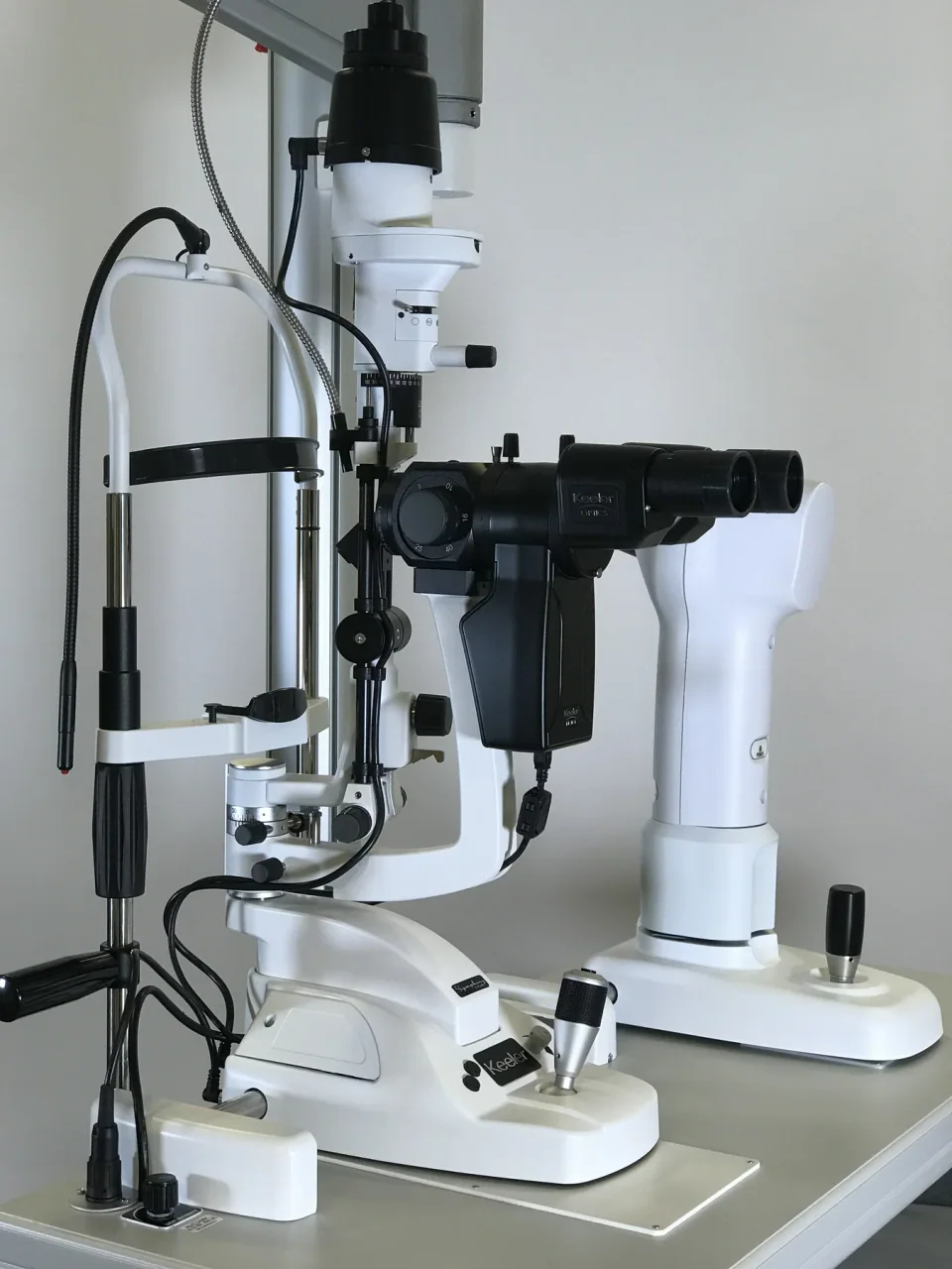 A Keeler table-mounted slit lamp with binocular eyepieces, chin rest and illumination arm.